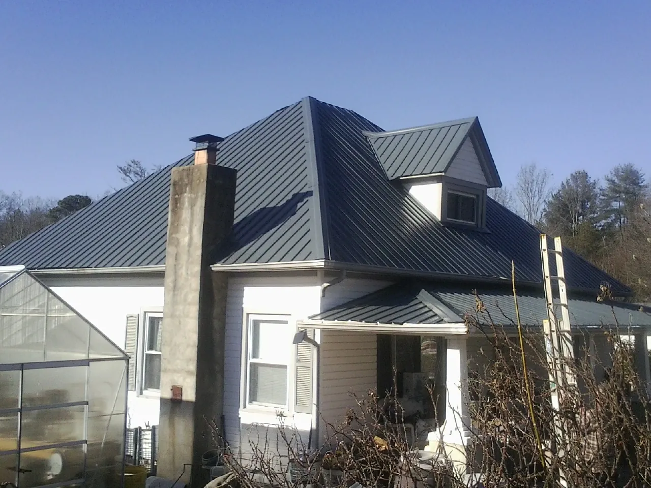 Dark blue standing seam metal roof on a white farmhouse with dormer — Slate & Tile Roof Repair by Roofing Brothers in Mineral Ridge