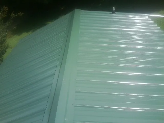 New green metal panels meeting at the ridge of a roof — Flat Roof Repair work by our crew in Mineral Ridge