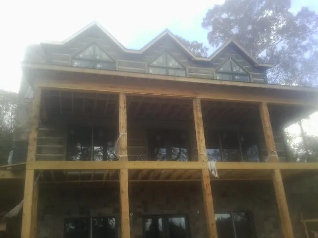 Dormers and porch framing on a large log home under construction — Roof Coating work by our crew in Mineral Ridge
