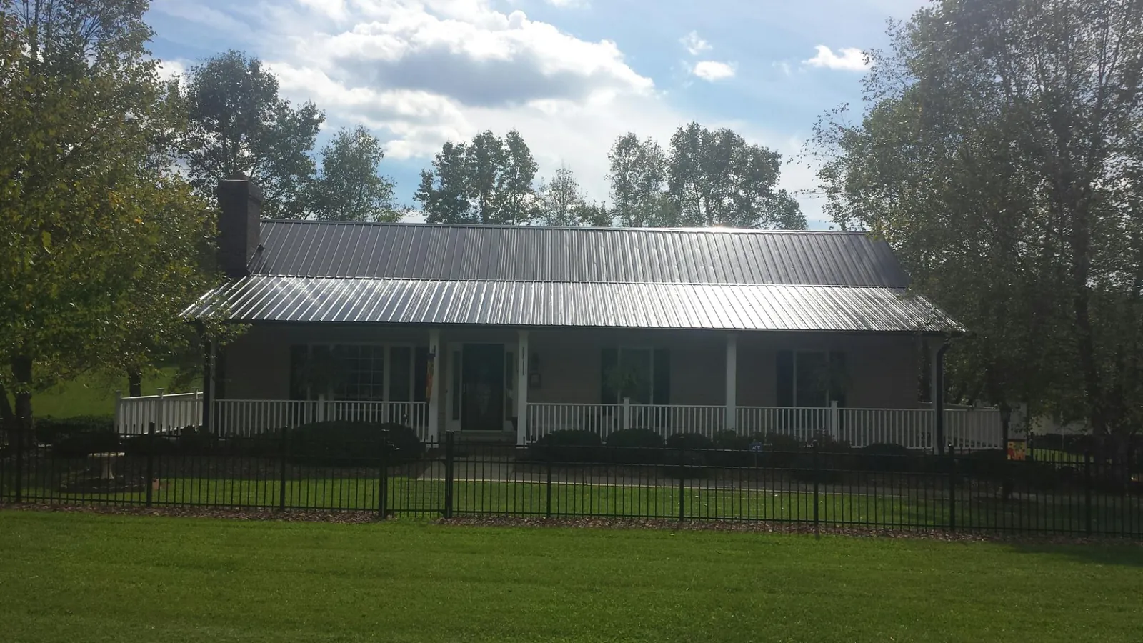 Gray metal roof on a brick ranch with a full width front porch — Gutter Guard Installation work by our crew in Mineral Ridge