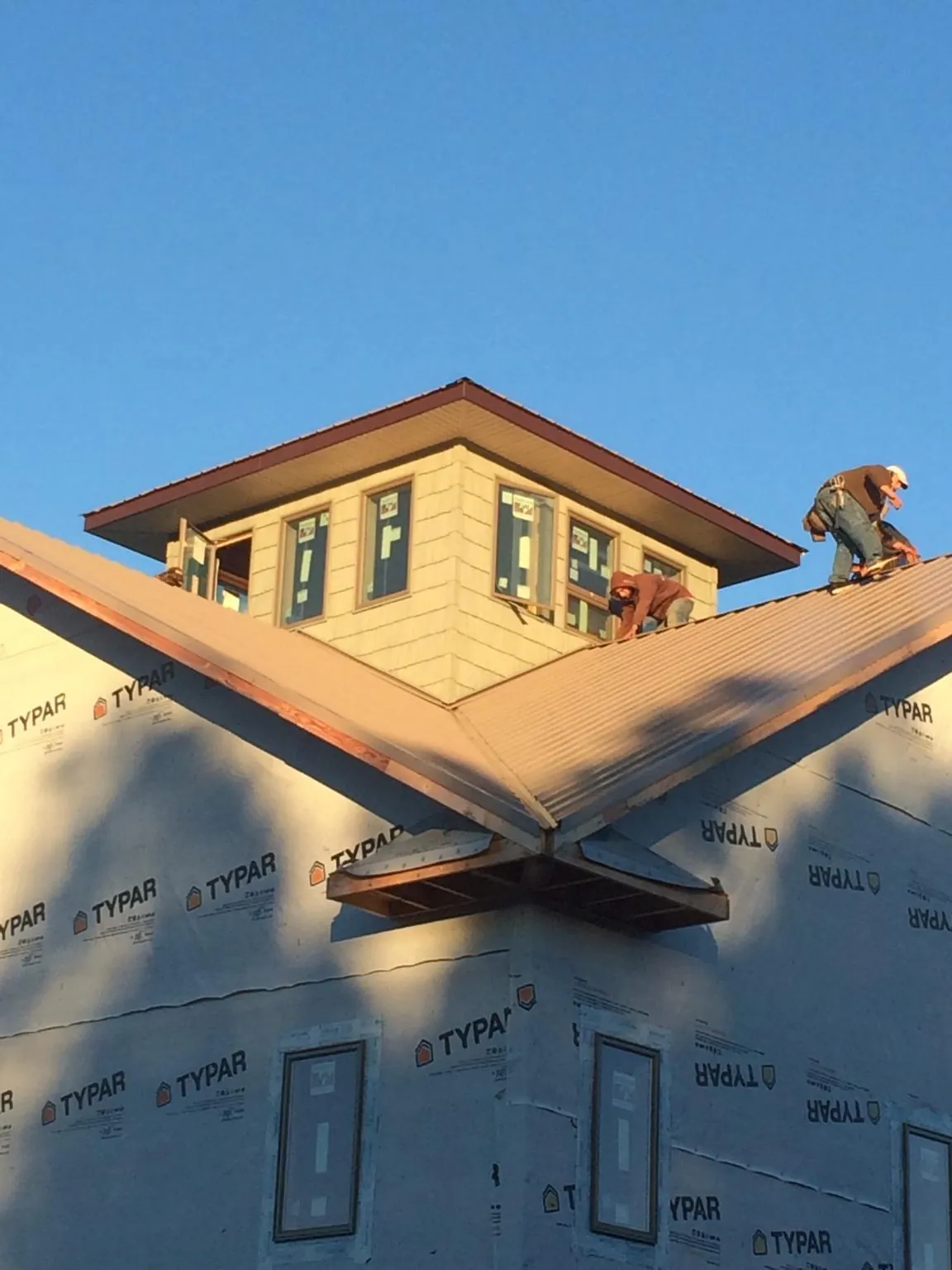Roofers working around a rooftop cupola on a new metal roof at sunset — Roof Waterproofing in Mineral Ridge by Roofing Brothers